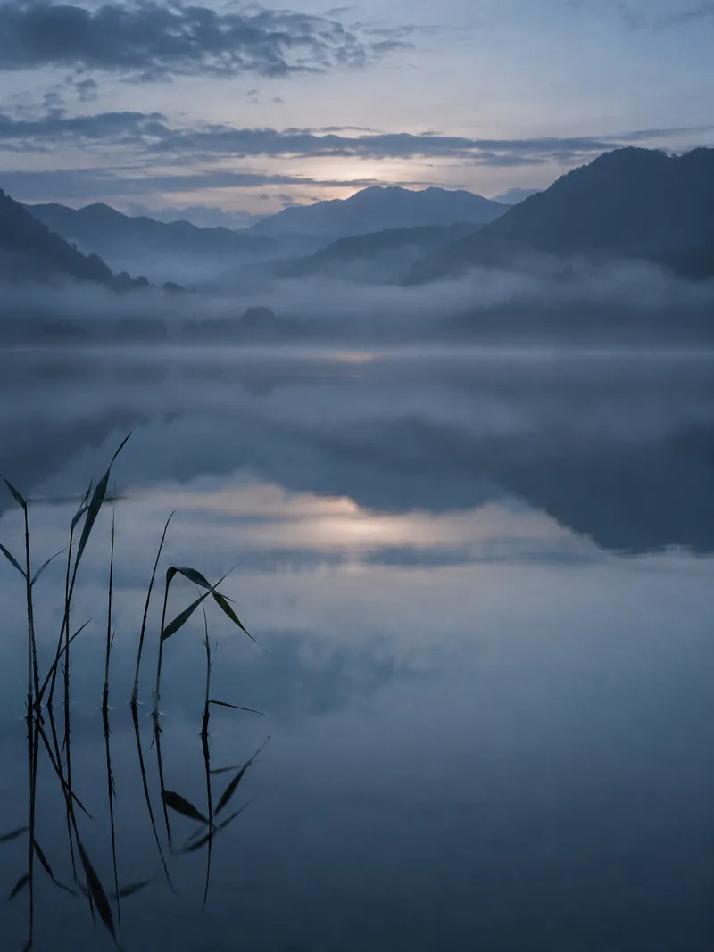 Reeds Before Reflected Mountains in Mist — AI-generated photograph
