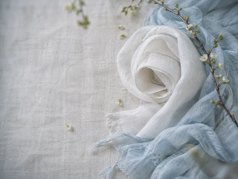 Rolled White Linen Beside a Blue Scarf — AI-generated photograph