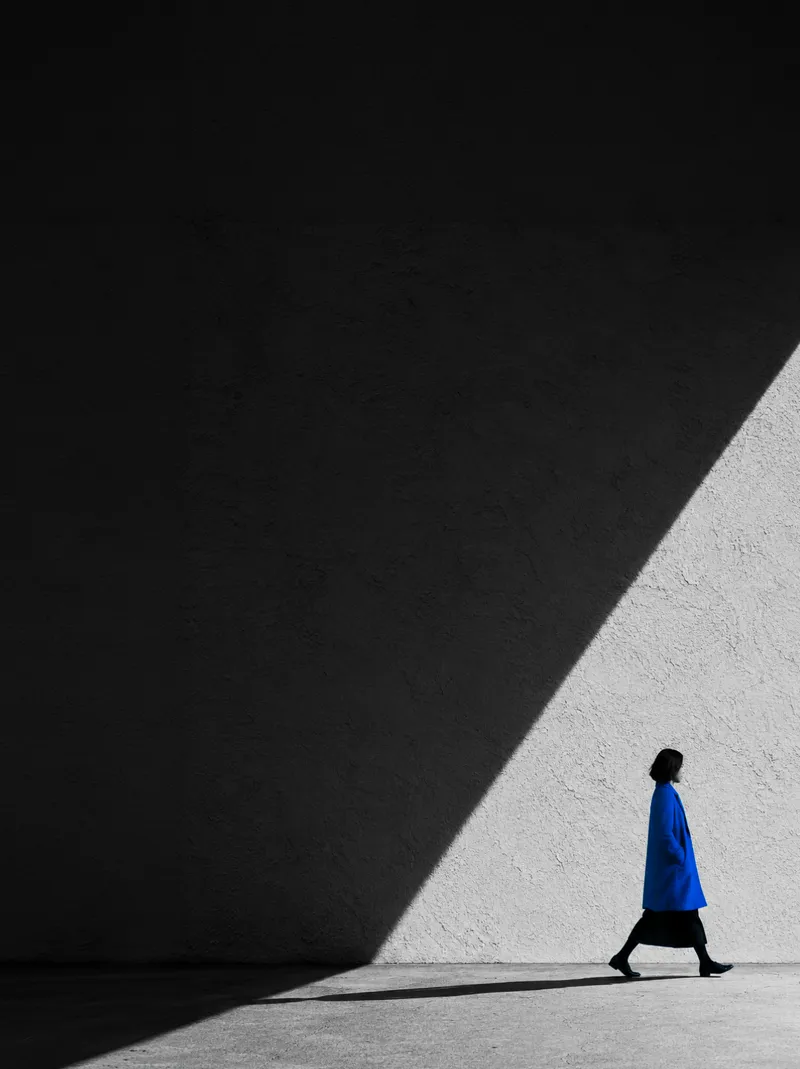 Woman in a Blue Coat Crossing Sunlight — AI-generated photograph
